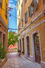 Charming narrow alley in the historic old town of Sibenik, Dalmatia, with colorful buildings and a traditional cobblestone path.Colorful Dalmatian houses with rustic shutters under a bright blue sky