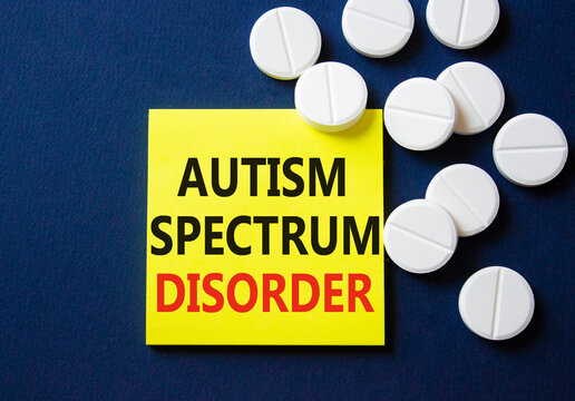 Autism Spectrum Disorder symbol. Concept word Autism Spectrum Disorder on yellow note. Beautiful deep blue background with pills. Medicine and Autism Spectrum Disorder concept. Copy space - Powered by Adobe