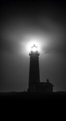 Dramatic black and white image of a lighthouse shining brightly through the darkness on a stormy night