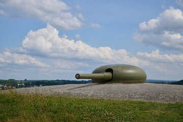 Historic artillery turret at Fort Halden Norway surrounded by grassy landscape under partly cloudy summer sky