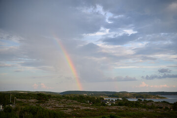 Rainbow Appearing Over Coastal Landscape Near Str&ouml;mstad, Sweden with Rocky Terrain, Islands, and Cloud-Filled Sky