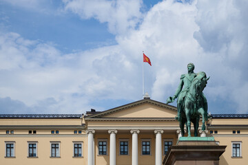 Front View of the Royal Palace in Oslo with Equestrian Statue and Norwegian Flag Against a Dramatic Cloudy Sky