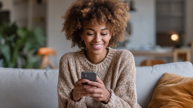 smiling afro american millennial woman user holding smart phone watching video playing game shopping chatting in mobile technology application sitting on sofa at home close up view banner design no l - Powered by Adobe