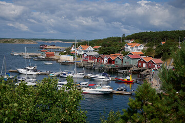 Colorful seaside village of Res&ouml; Bohusl&auml;n with boats moored in scenic harbor surrounded by rocky coast and greenery
