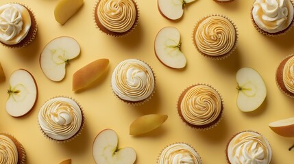 Flat lay of cupcakes with swirled cream frosting and apple slices scattered on a pastel yellow background, creating a bright and appetizing dessert composition.