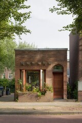 A delightful brick building adorned with charming window plants stands gracefully in a peaceful neighborhood, basking in the warmth of a sunny day