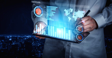 A business professional uses a futuristic touchscreen tablet to interact with complex graphs and data visualizations, set against a nighttime city skyline. Impute