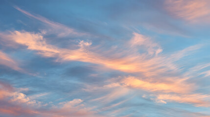 Obraz premium Wispy clouds tinged with peach and gold against a serene blue sky sunset sunrise