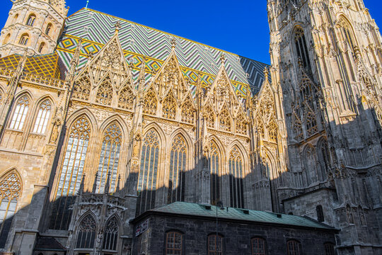 Sunlit Gothic facade with colorful tiled roof in Vienna&rsquo;s iconic cathedral.