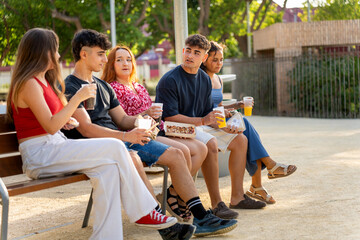 Group of generation z friends enjoying drinks and food in a park
