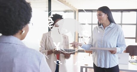 Woman explaining finance trends driving globe with currency symbols as colleague tapping laptop - Powered by Adobe