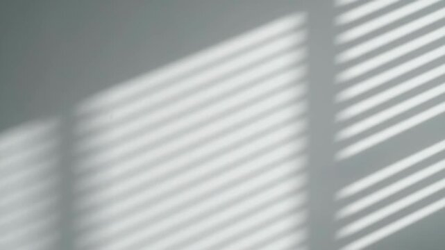 Sunlight Stripes Through Blinds - Soft sunlight filters through window blinds, casting delicate, parallel stripes of light and shadow onto a light gray wall.