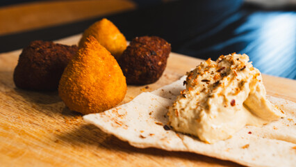Creamy hummus with flaky chicken pastries (fatayer-style) and crispy kibbeh. Authentic Middle Eastern sharing plate for food blogs and gourmet menus.