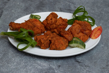 Crispy Thai Fried Chicken with a Garnish of Spring Onion and Cucumber Slices in plate top view of street food