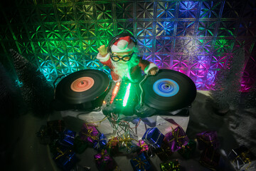 Christmas and New Year club concept. Dj mixer with headphones on snow. Santa Claus is mixing on turntable. Creative miniature