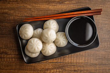 Xiao long bao. Chinese dumplings and soy sauce on wooden table. Top view.