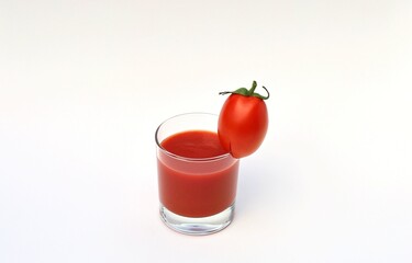 A glass of tomato juice. With a small tomato on the edge.