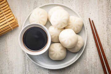 Xiao long bao. Chinese dumplings on plate and soy sauce on kitchen table. Top view.