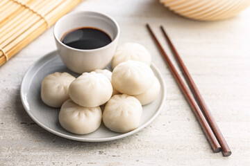 Xiao long bao. Chinese dumplings on plate and soy sauce on kitchen table.