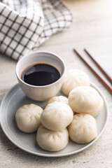 Xiao long bao. Chinese dumplings on plate and soy sauce on kitchen table.