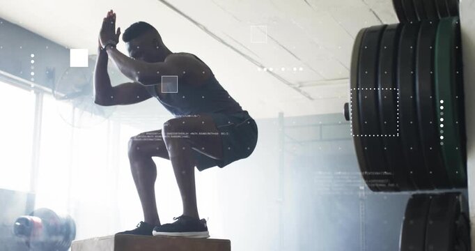 Male athlete shifting into squat, jumping onto plyometric box, landing near gym windows for fitness