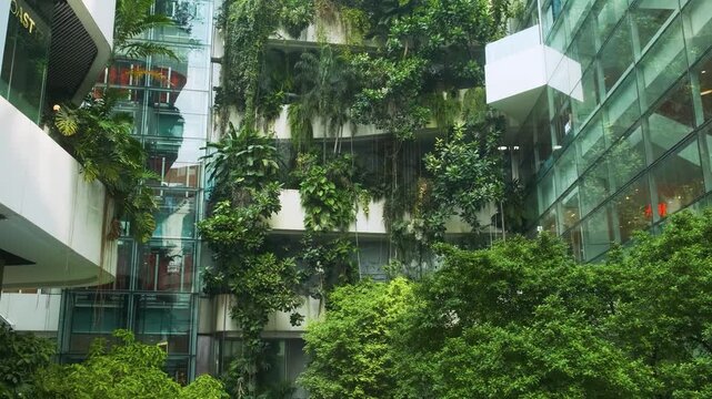 Modern eco-friendly shopping mall building facade with vertical garden, green plants and waterfall in urban environment in Bangkok city, Thailand. Green architecture and sustainable design