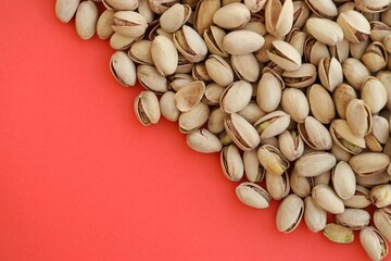 Tasty unpeeled pistachios on bright red background, top view flat lay background pattern