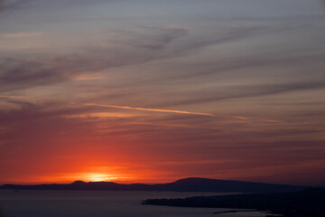 Fiery Sunset over Coastal Mountains – Dramatic Sky and Silhouetted Horizon