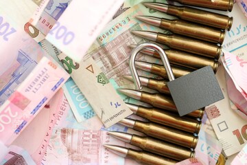 Big amount of different Ukrainian hryvnia money bills and bullets with padlock
