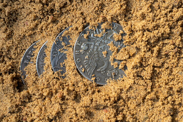 Antique silver coins in the sand.Find a treasure trove of antique coins.Treasure hunters.