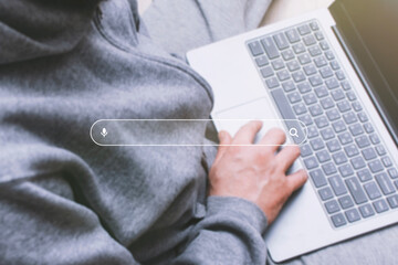 Man using a laptop, with a digital search bar and magnifying glass icon overlaid on the image. Concept of online searching, digital research, and casual internet use.