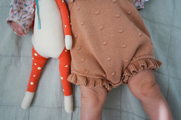 Baby with soft toy lying on bed ? cozy childhood moment, top view.