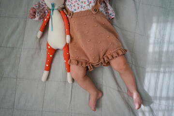 Baby with soft toy lying on bed ? cozy childhood moment, top view.