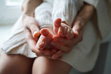 Little baby feet in mother's hands, close-up