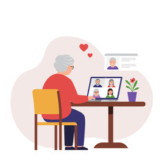 Elderly woman video calling family while sitting at table with laptop  