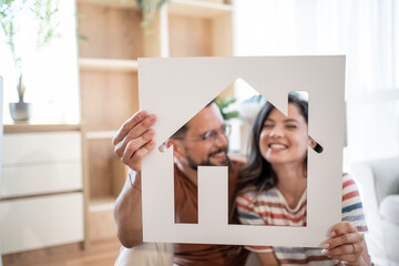 Happy couple holding a house sign, representing their new home