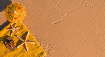 top view of paper beach with yellow towel, umbrella and starfishes on sand near ocean