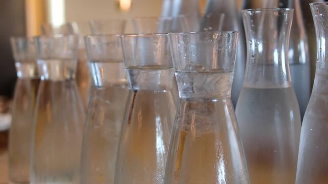 many glass water lilies stand in a row on the counter in a buffet restaurant. jugs with water. High quality 4k footage