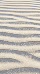 Obraz premium Close-up of white sand texture with subtle wave patterns and shadow, creating a serene and minimalist appearance, ideal for background or design element