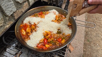 Rice in the shape of a cross in paella. Traditional spanish seafood paella being prepared outdoors with fresh ingredients. Valencian cuisine. Stage of cooking paella. Ingredients for paella