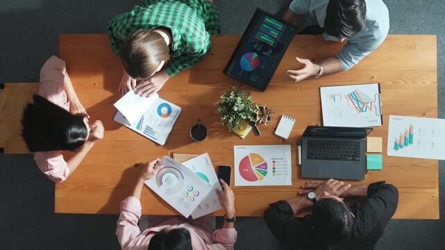 Top view of project manager using tablet to analyze data and financial chart while marketing team working together to brainstorm marketing campaign or planning strategy at meeting room. Convocation. - Powered by Adobe