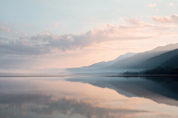Obraz premium Serene lake surface reflecting soft morning light and pastel sky.
