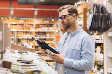 Customer Choosing Wine Bottle in Supermarket Drinks Section