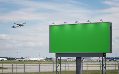 billboard with green screen on airport runway perimeter fence, airplanes in background