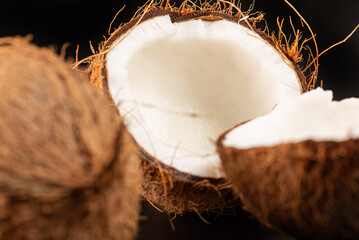 Coconuts placed on a dark surface and black background, low key photo, selective focus.