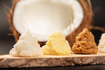 Open coconut and coconut sweets (cocadas) placed on a dark surface, black background, selective focus.