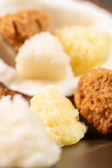 Open coconut and coconut sweets (cocadas) placed on a dark surface, black background, selective focus.