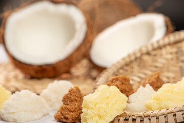 Open coconut and coconut sweets (cocadas) placed on a rustic wooden surface, selective focus.