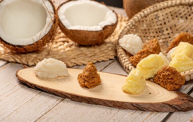 Open coconut and coconut sweets (cocadas) placed on a rustic wooden surface, selective focus.