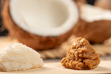 Open coconut and coconut sweets (cocadas) placed on a rustic wooden surface, selective focus.